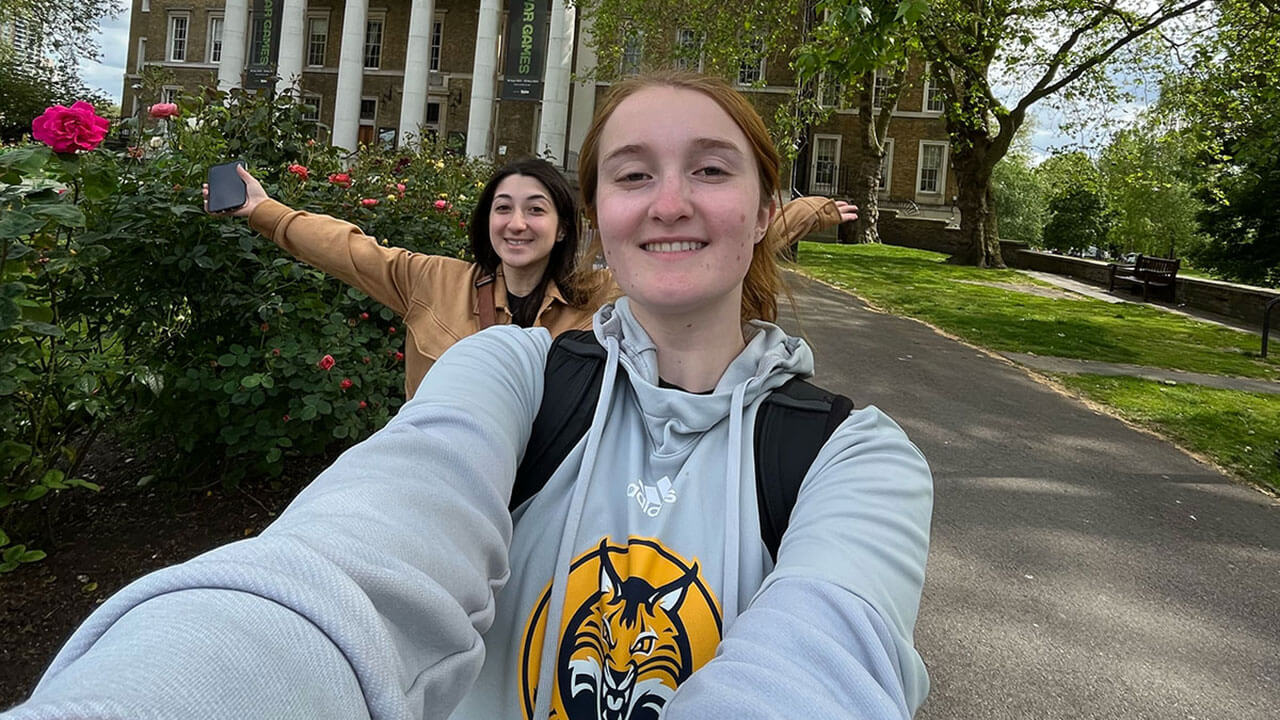 two students pose for a selfie in a park