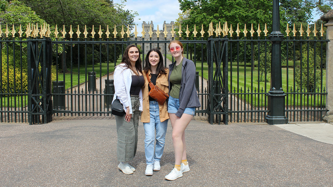 three students pose in front of the gates at windsor castle
