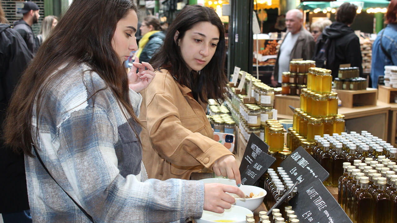 two students taste the different truffle oils at a market