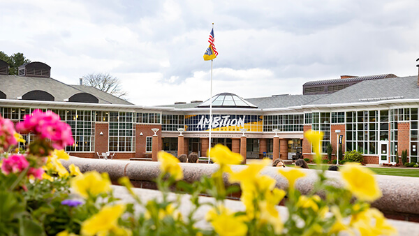 The Carl Hansen Student Center surrounded by spring flowers with Ambition Unleashed written in the windows.