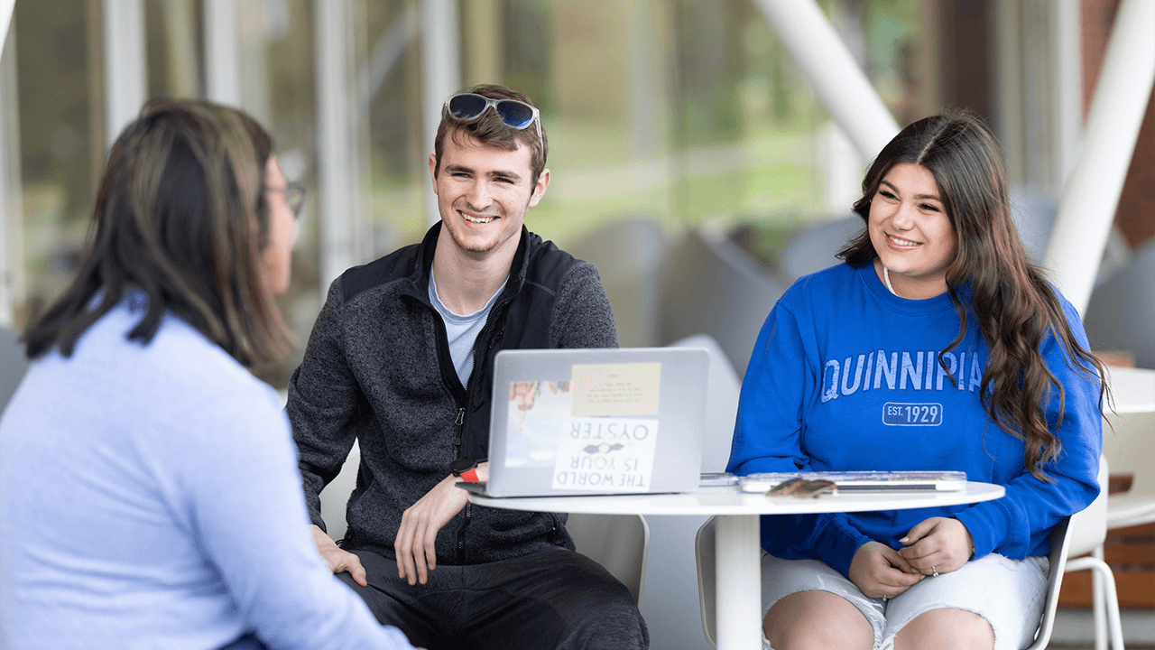 Two Quinnipiac students speak with an admissions counselor on campus