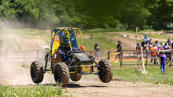 Quinnipiac's Baja vehicle drives across the competition course leaving a cloud of dust.