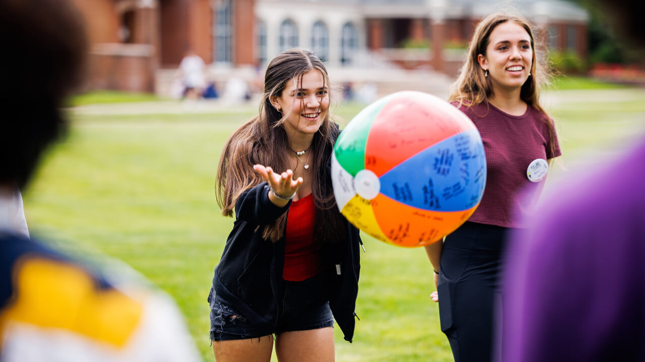 A new student tosses a beach ball in front of her