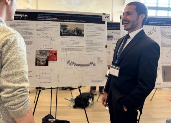 Benjamin Anasis standing in front of poster