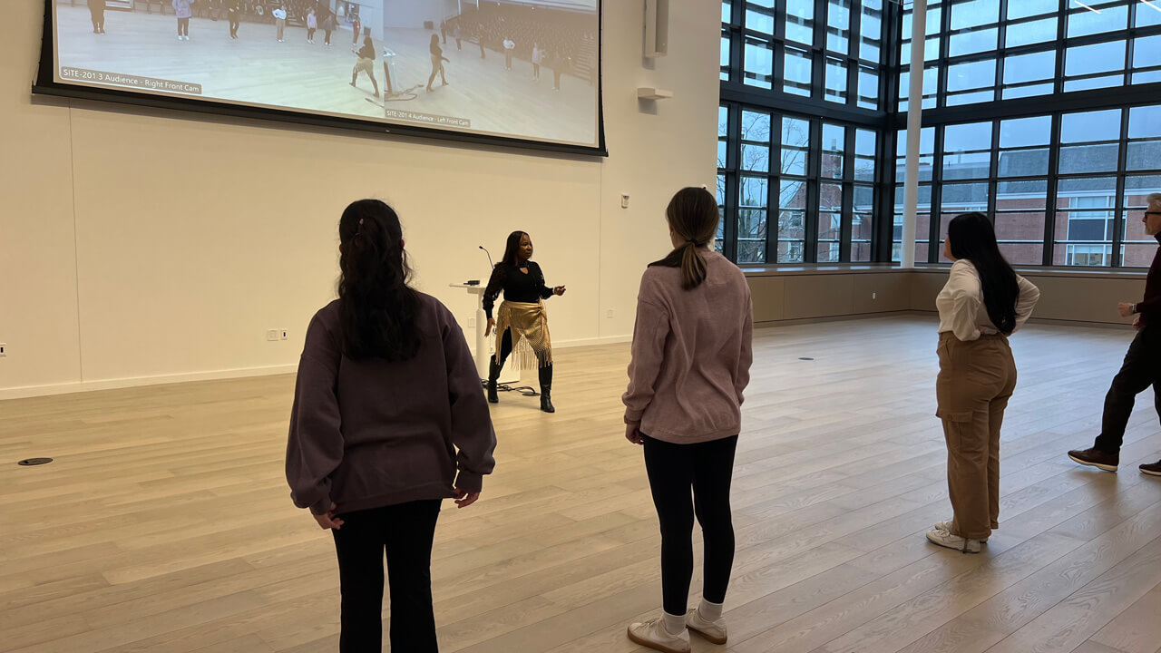 Three female students shown from behind facing the instructor during the salsa dancing workshop.