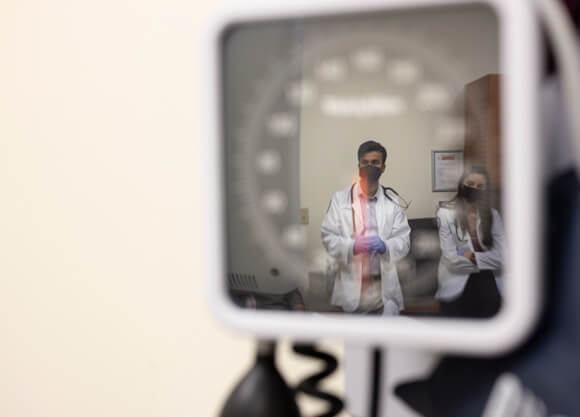 Quinnipiac medical students in the reflection of a blood pressure gauge.