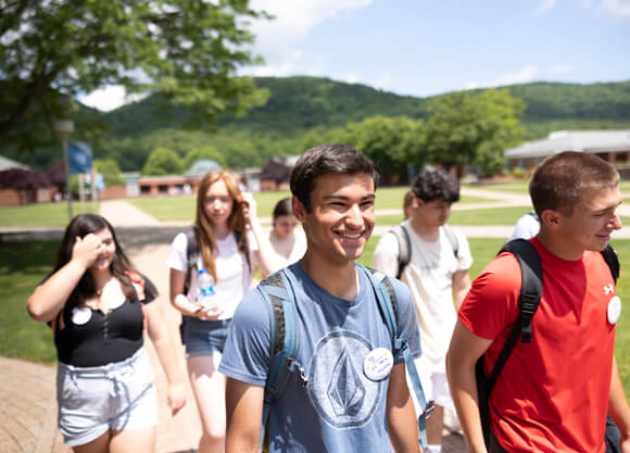 New students smile as they walk across a sunny quad during Orientation