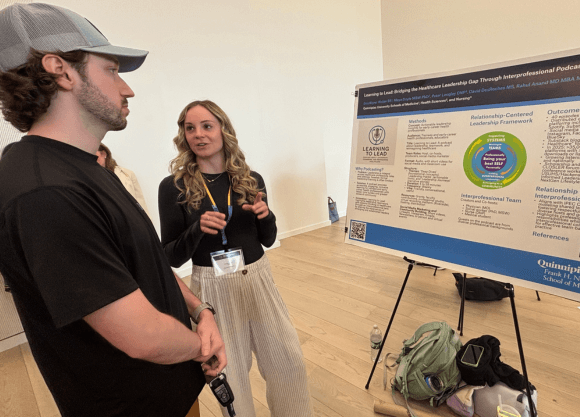 Photo of Brooklynn Weber standing in front of poster project and speaking to a male viewer