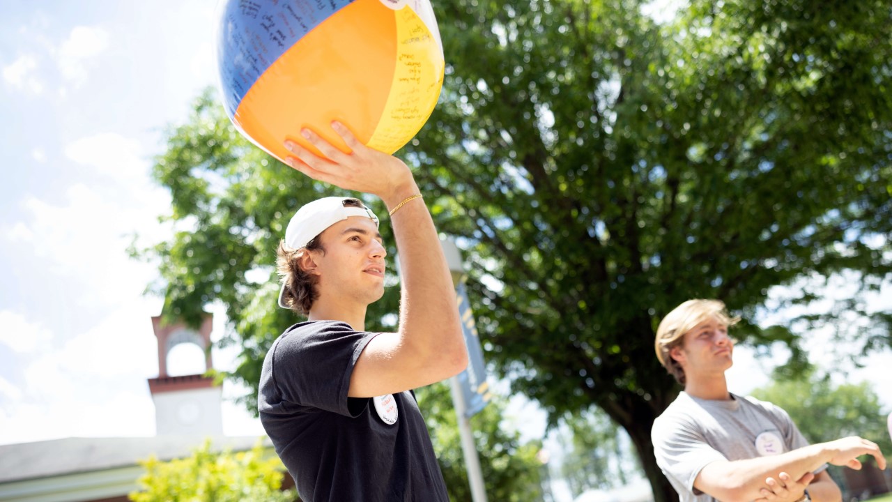 A student holds a beach ball at orientation.