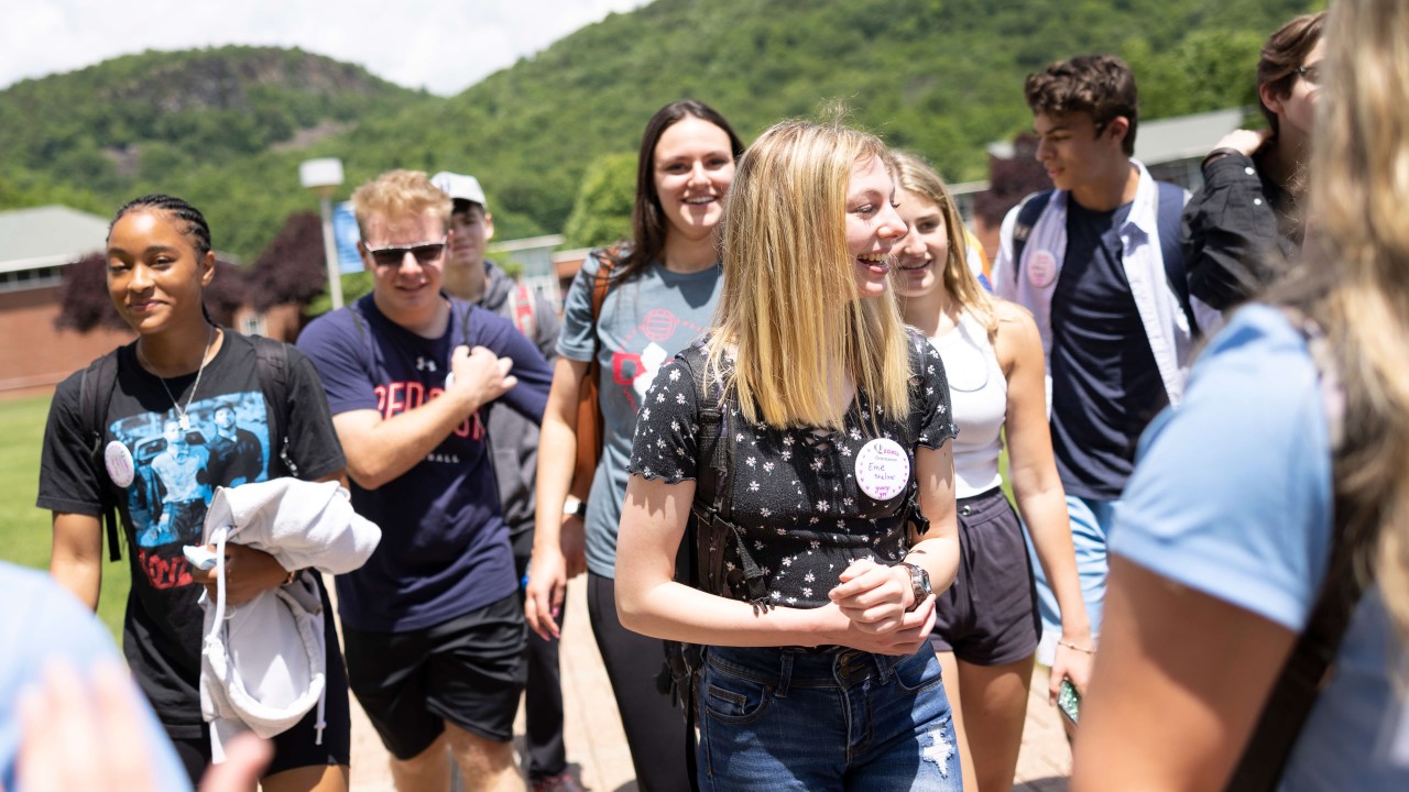 A group of students at orientation smile and laugh as they walk across the quad.