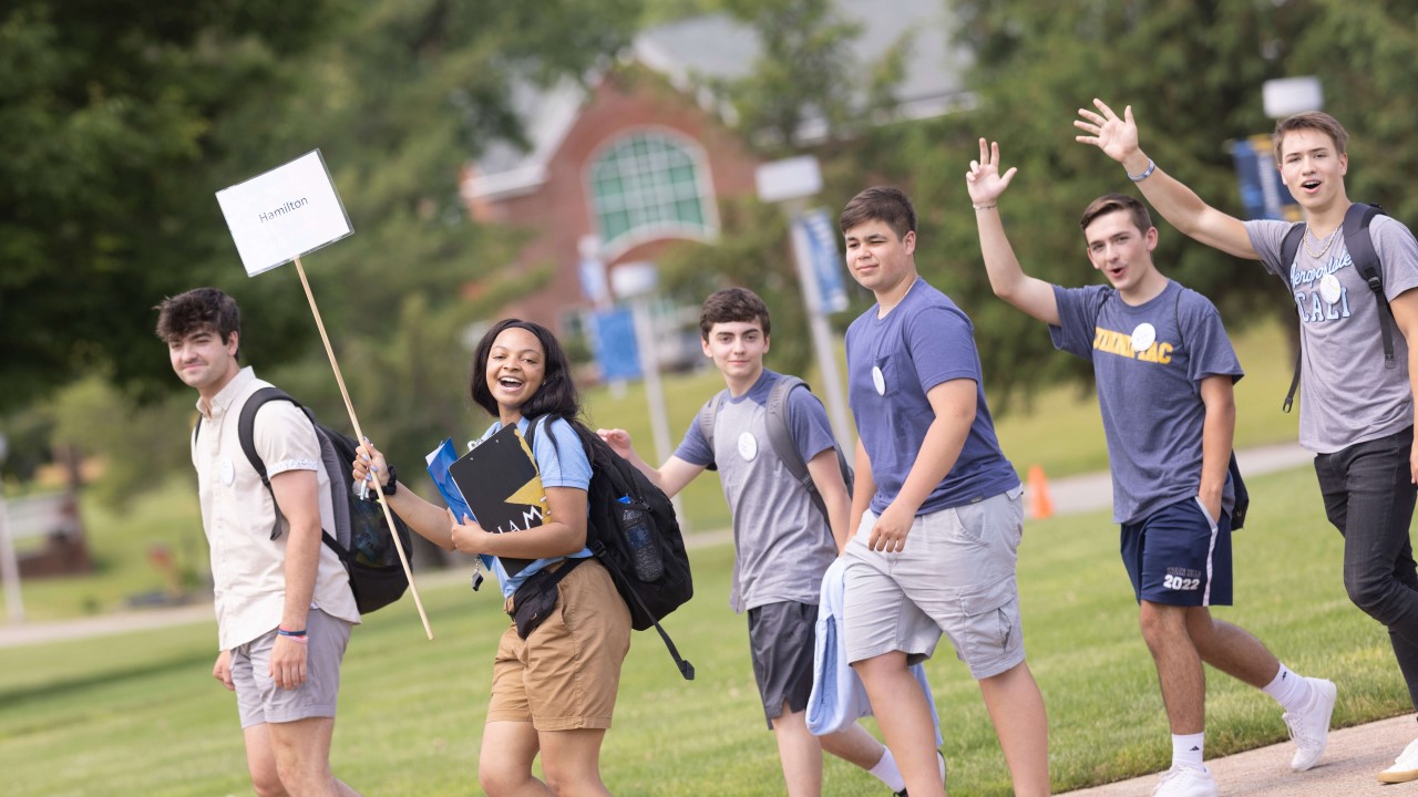 Orientation leader leads a group of students across the quad.