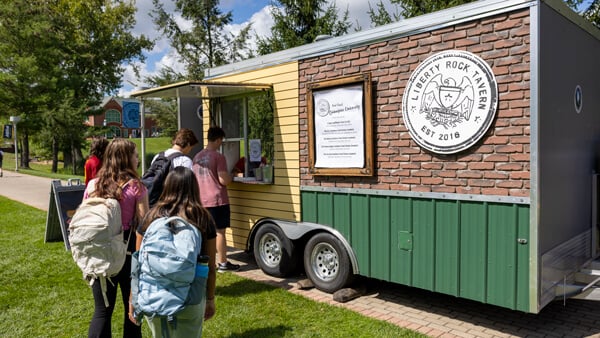Students in line get food from a food truck on the Mount Carmel Campus quad