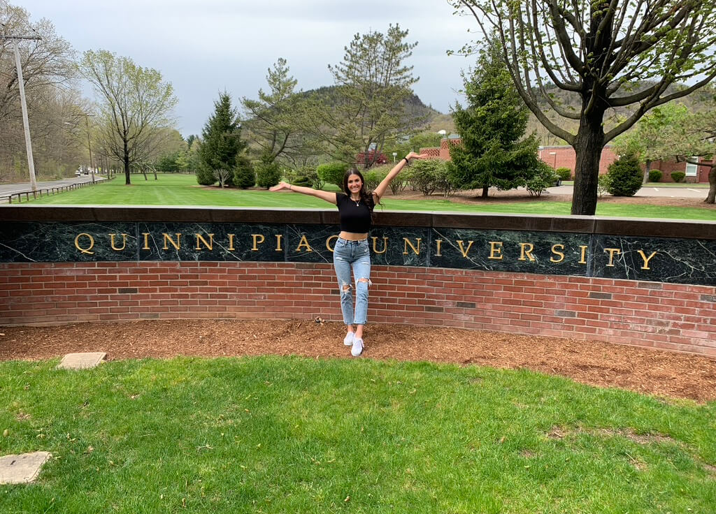 Kayla Birmingham in front of the Quinnipiac University wall on the Mt. Caramel campus