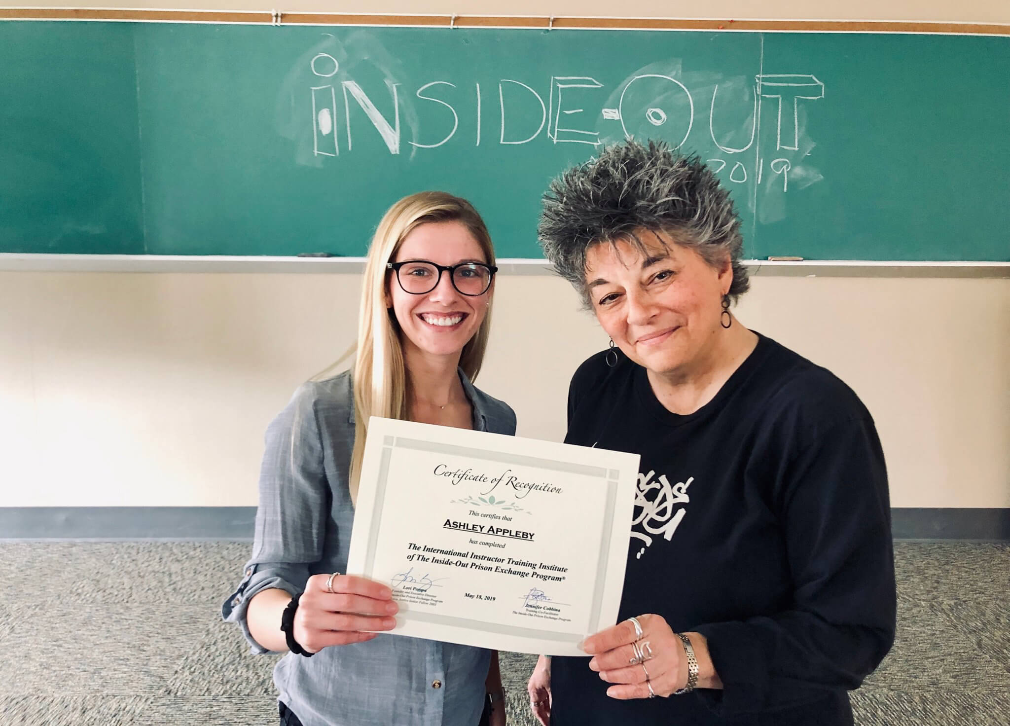 Alumna stands with teacher with certification