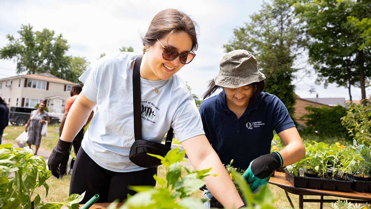 Two quinnipiac students smiling while planting