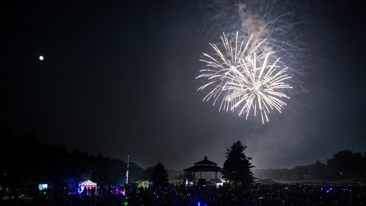 Two white fireworks explode over the Hamden town green and gazebo