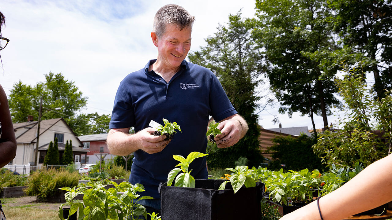Quinnipiac faculty member smiling as he looks down at the plants he's holding
