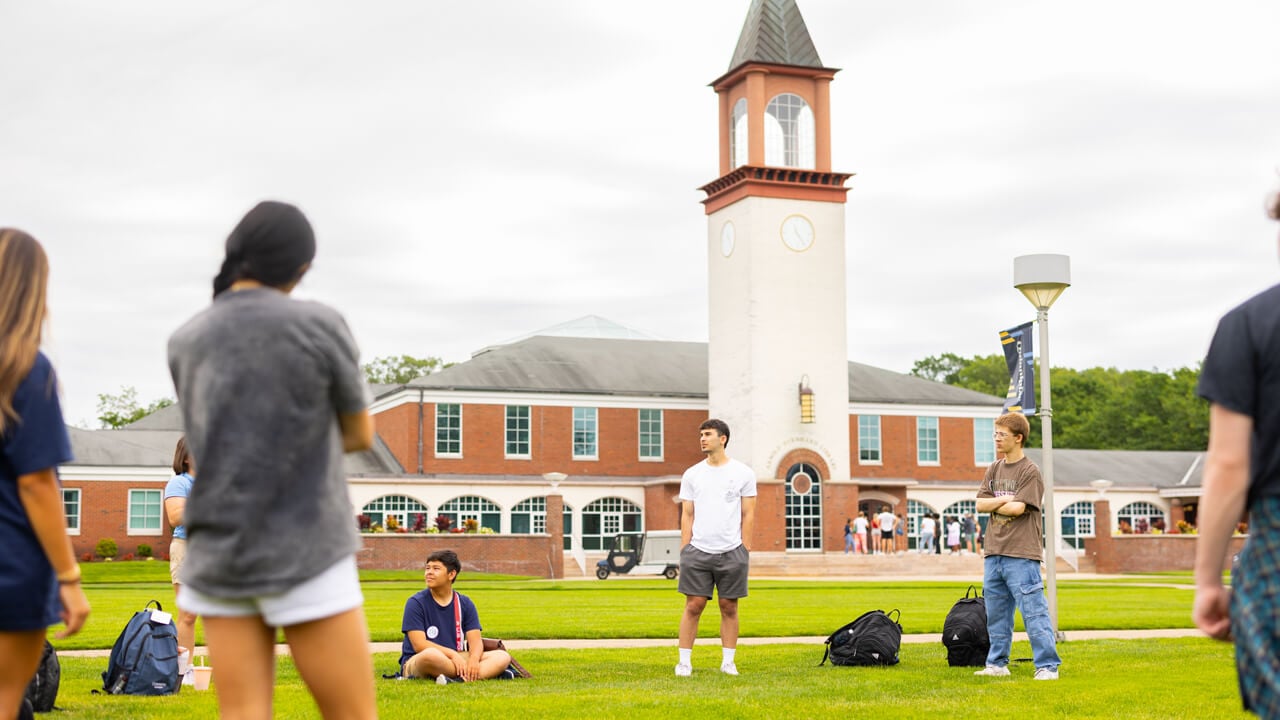 Individuals standing and sitting on the Quad during Orientation