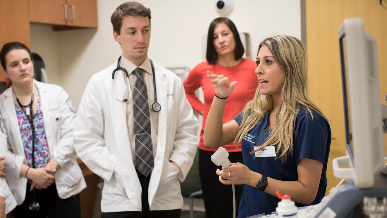Quinnipiac medical student gives direction to other medical students in a hospital room.