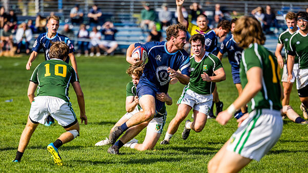 Quinnipiac club men's rugby team plays against another team on a field.