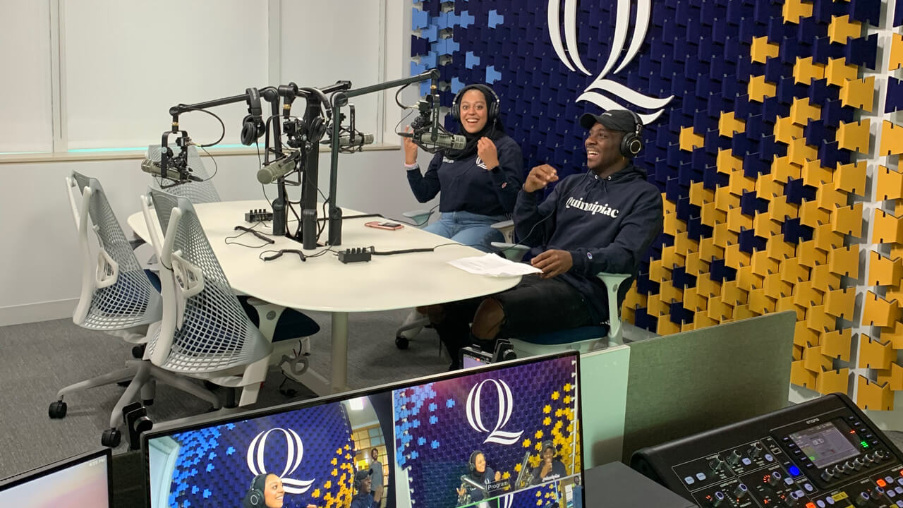 Two communications students record an episode in the Quinnipiac podcast studio