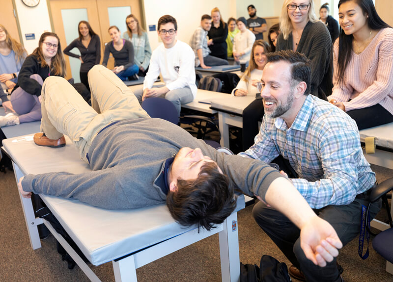 Professor Jason Scozzafava, DPT demonstrates a therapeutic stretch with a student in his classroom