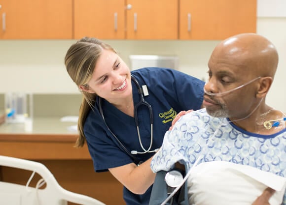 Quinnipiac Nursing student smiling next to an elderly patient