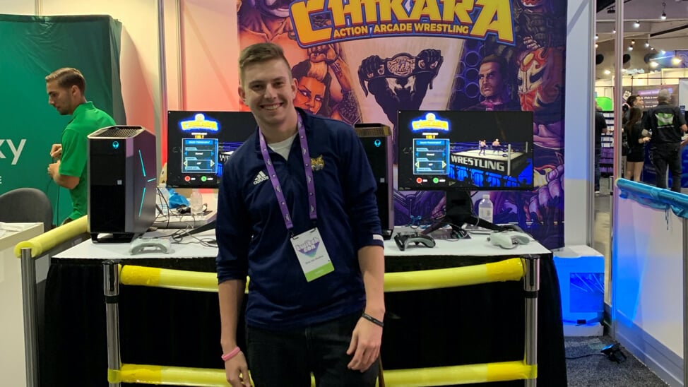 Alumni Chad Reilly standing in front of a booth at a gaming convention