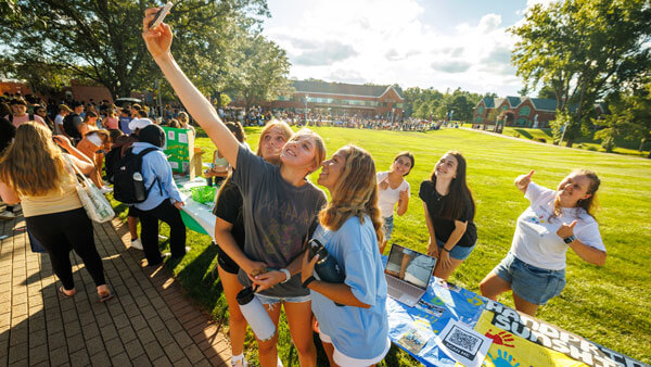 Girls taking selfie with iPhone on the Quad during Engagement Fair