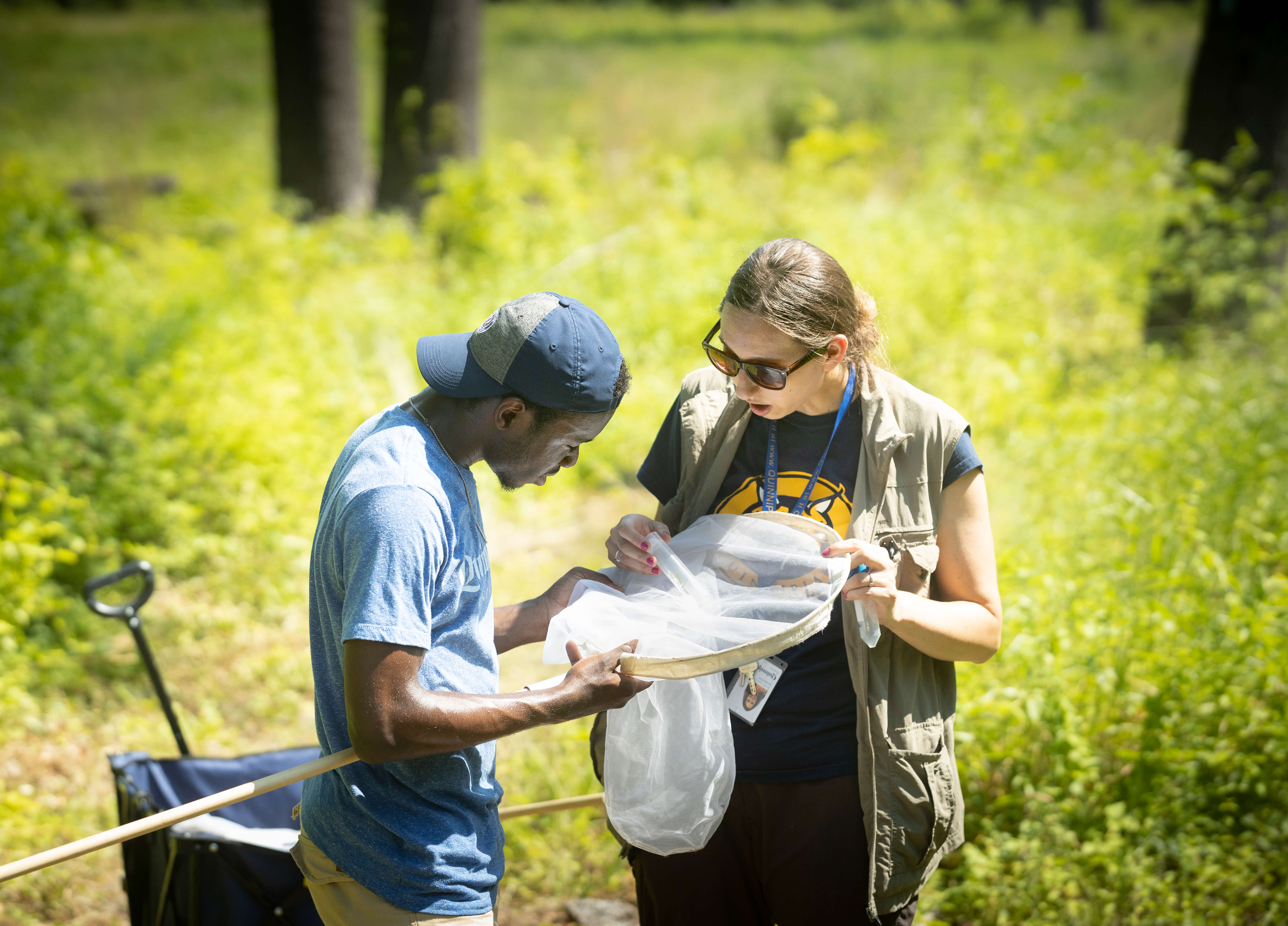 Sarah Lawson and student stand in field with net studying a bee they caught