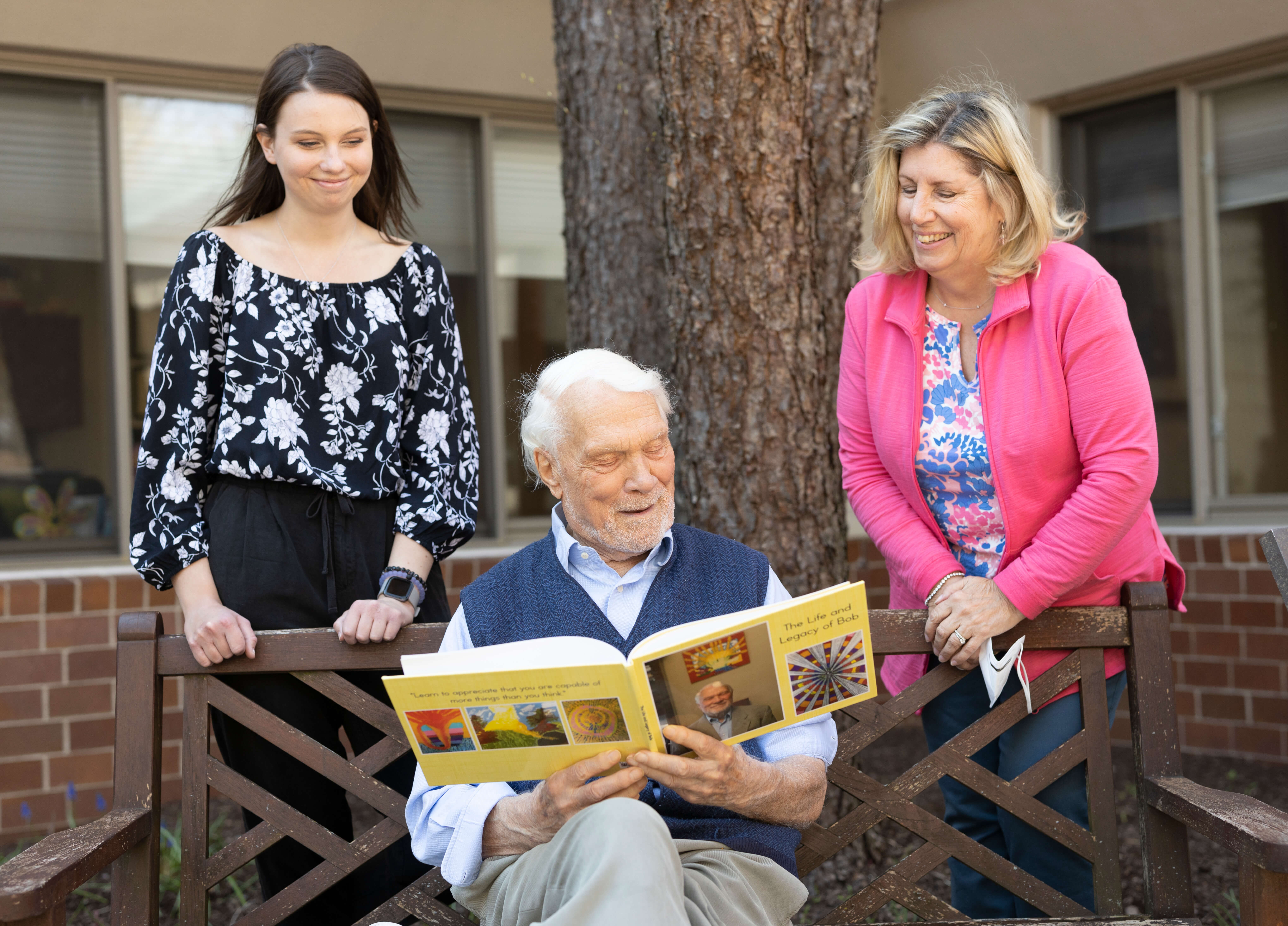 Bob Savage, a resident of LiveWell Dementia Specialists facility, reads from his Legacy book to volunteers Jessica Leach and Janet Waldman