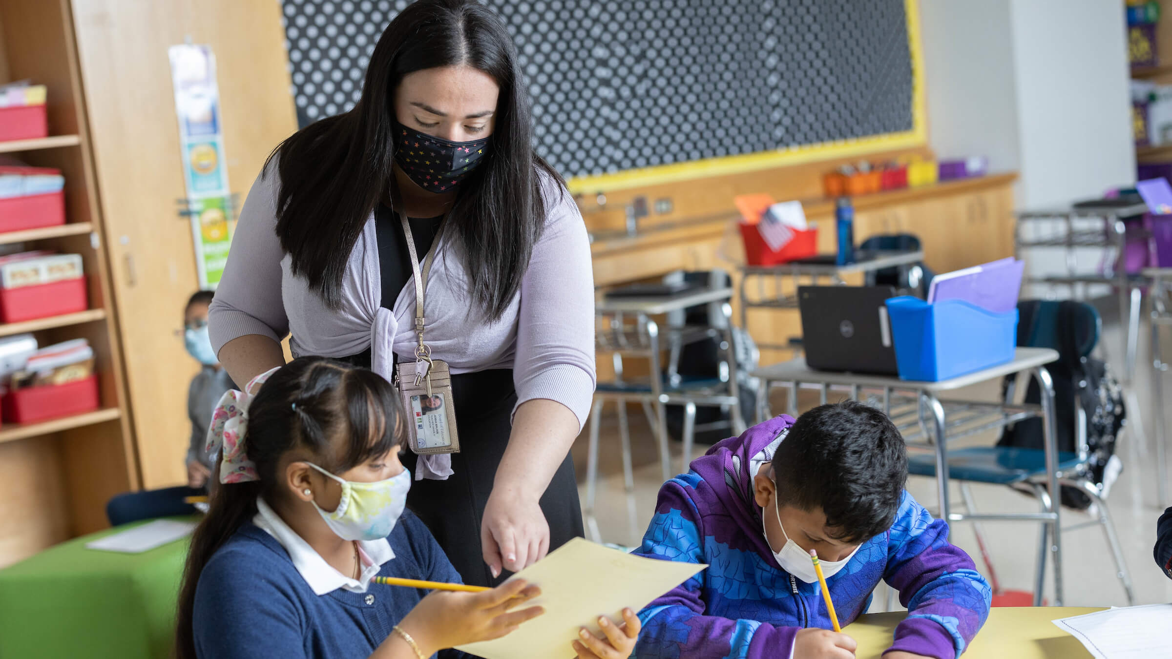 enna Malkin teaching in her classroom with two students with masks on