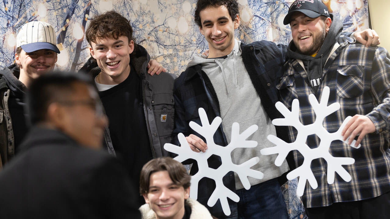 Group of men smiling and laughing while holding fake snowflakes