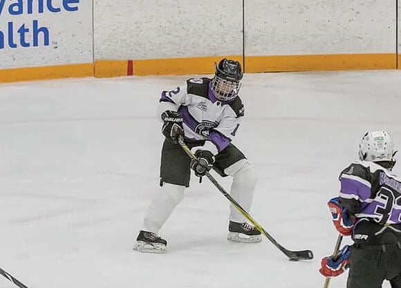 Gillian Gallagher on the ice in hockey gear playing with her hockey stick