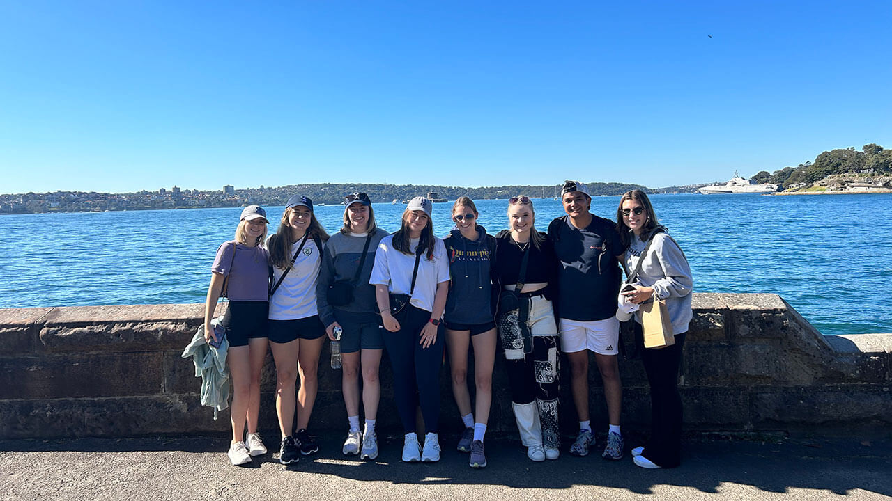 A group of students in Sydney, Australia, take a group picture by the water