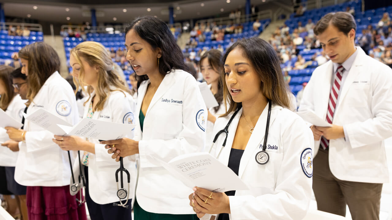 Medical students stand and read aloud from the white coat program