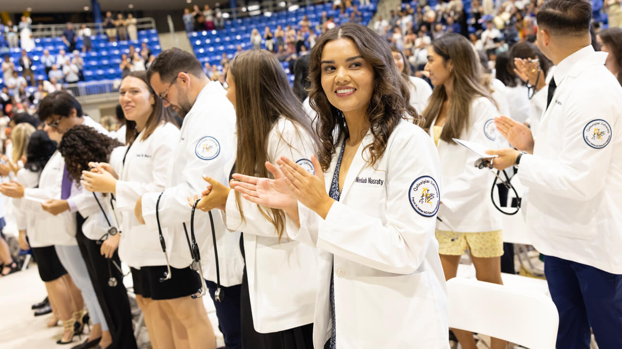 Medical students wear their white coats, smile and clap during the White Coat Ceremony
