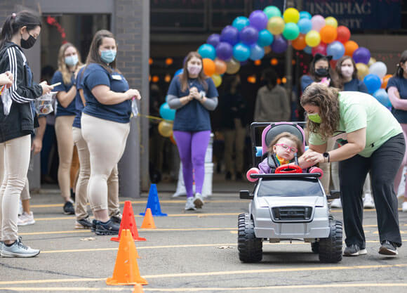 Child takes a ride on a grey toy truck at go baby go event