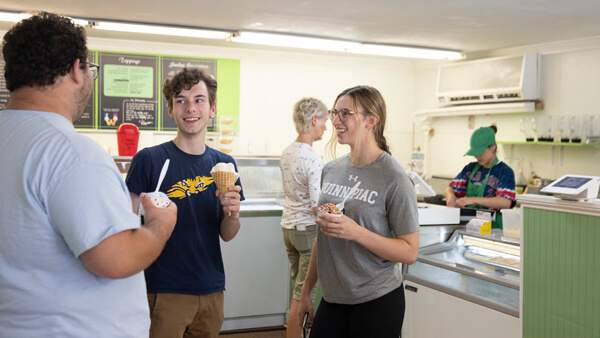 Three students talk as they eat ice cream at Wentworth's ice cream shop