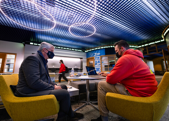 Dean of the School of Communications, Chris Roush talks with student, Dan Passapera in the SOC lobby.