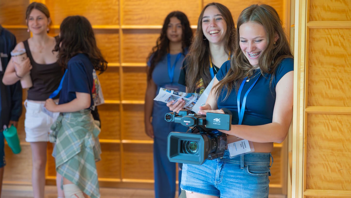 A high school student holds a video camera with a big smile during the Quinnipiac movie making summer camp.