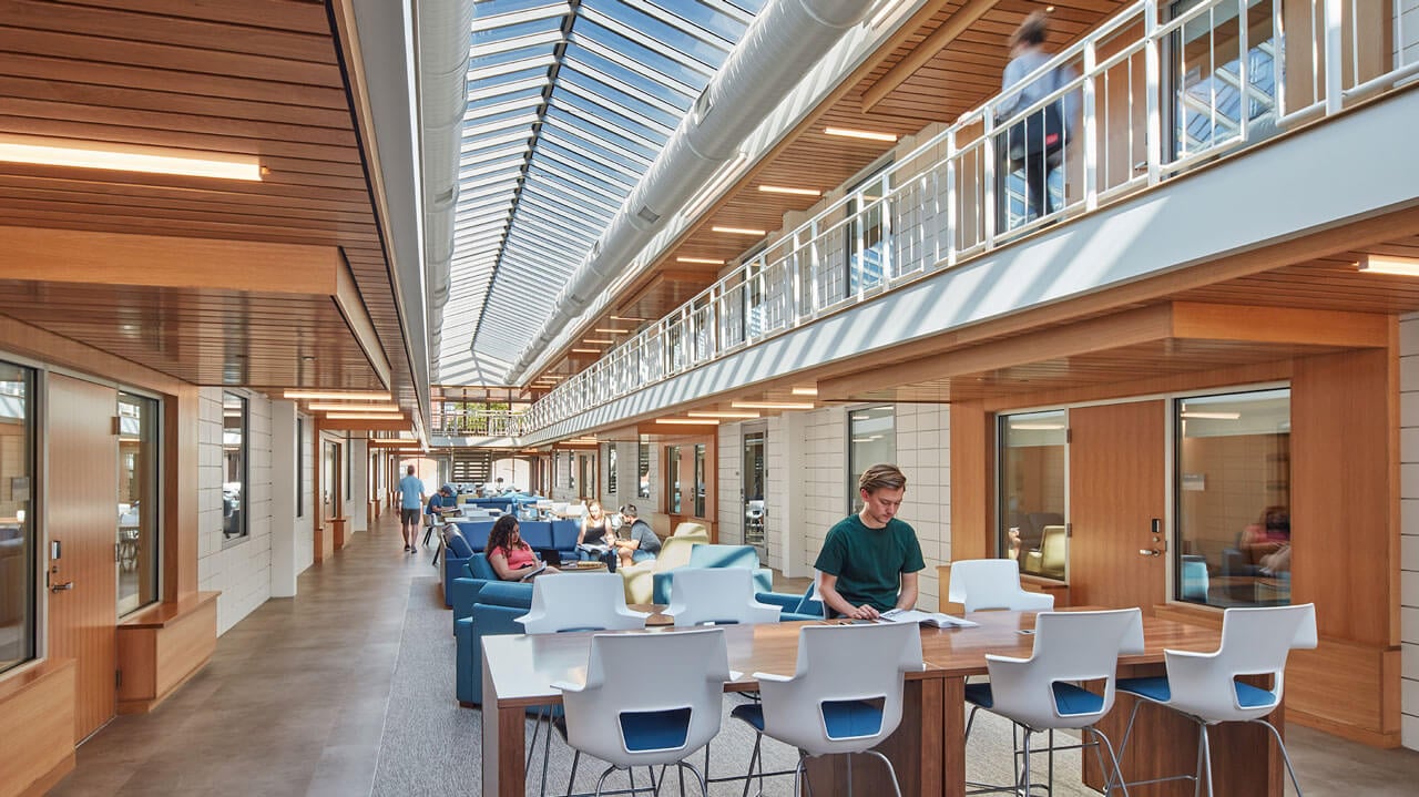 Students walk or sit in the two-story atrium of the renovated Perlroth dorm