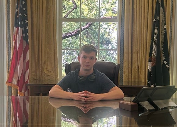 Chris Carver '27, MS '28, sitting at an office desk in Washington, D.C.