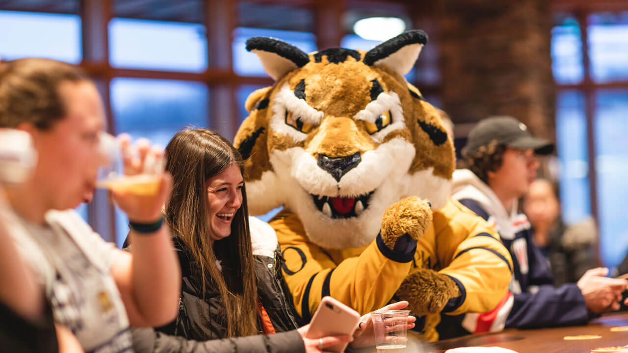 Boomer the mascot sits next to a laughing student in the pub
