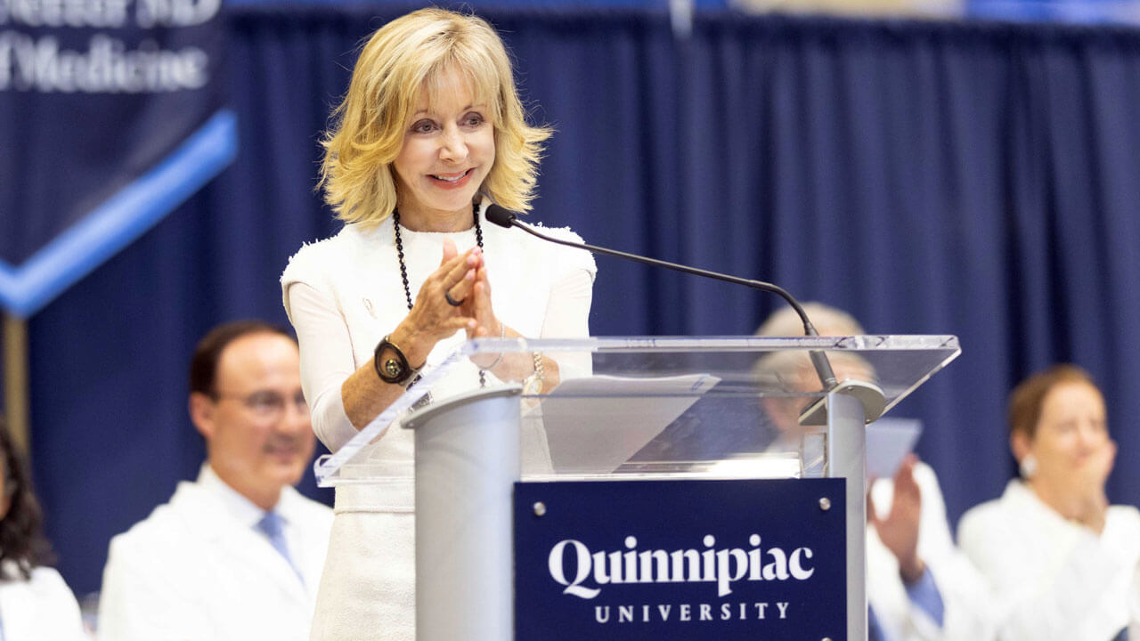 President Judy D. Olian smiling and standing up at the podium during ceremony