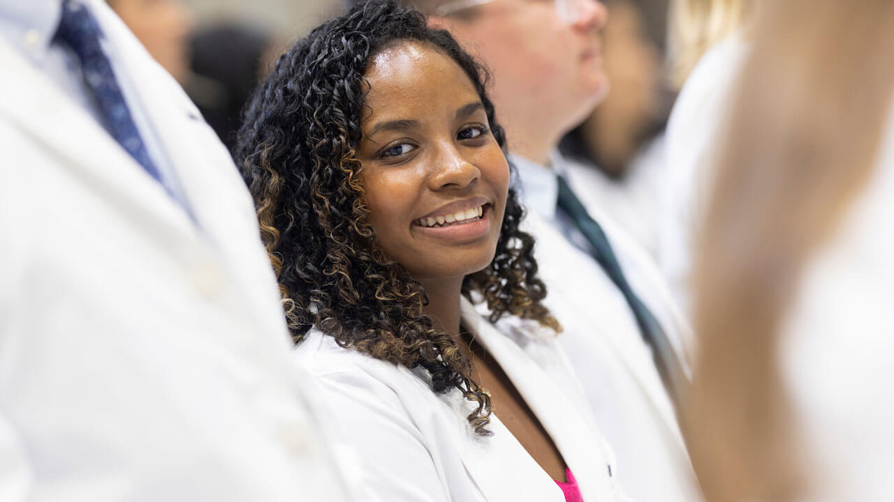 Student sitting and smiling after receiving her white coat
