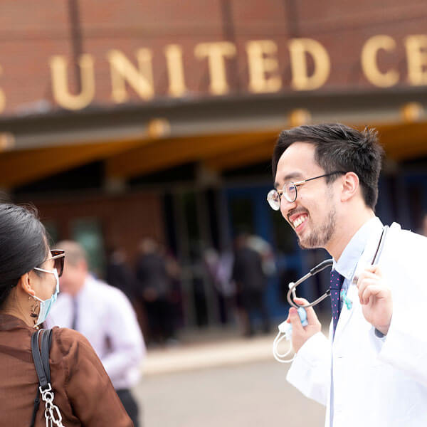 Seungju Hwang wears his white coat and smiles outside after the White Coat ceremony