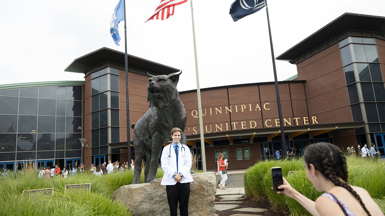 Student poses in front of bobcat statue.