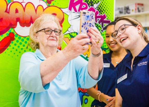 Two OT students teach one of the adults how to take a selfie