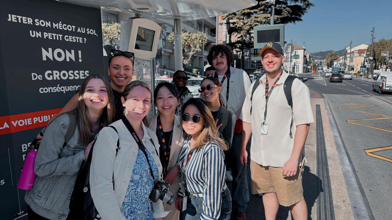 A group of students take a picture outside the Cannes Film Festival on a faculty-led trip abroad